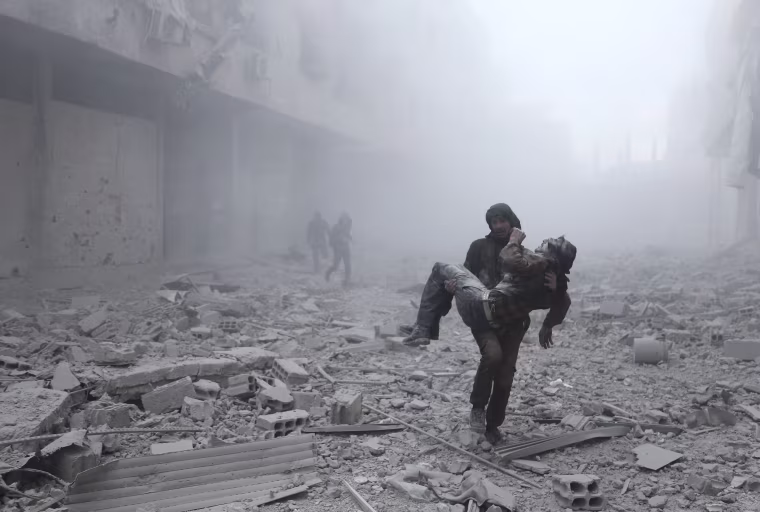 Image: A wounded man is carried following an air strike in Ghouta