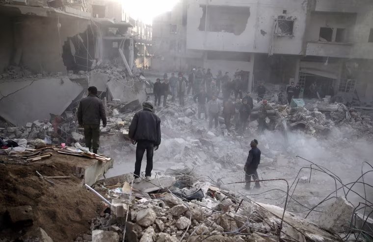 Image: People gather after airstrike in the besieged town of Hamoria, Damascus