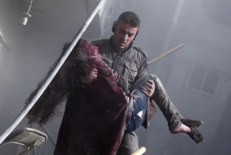 Image: A volunteer from the Syrian Civil Defense carries a wounded girl