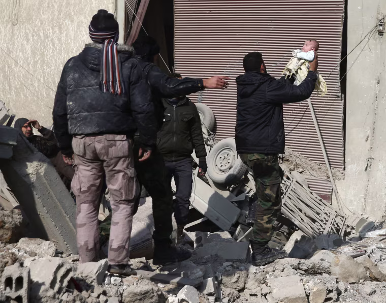 Image: Man holds a wounded child after an airstrike in the Saqba area, Damascus