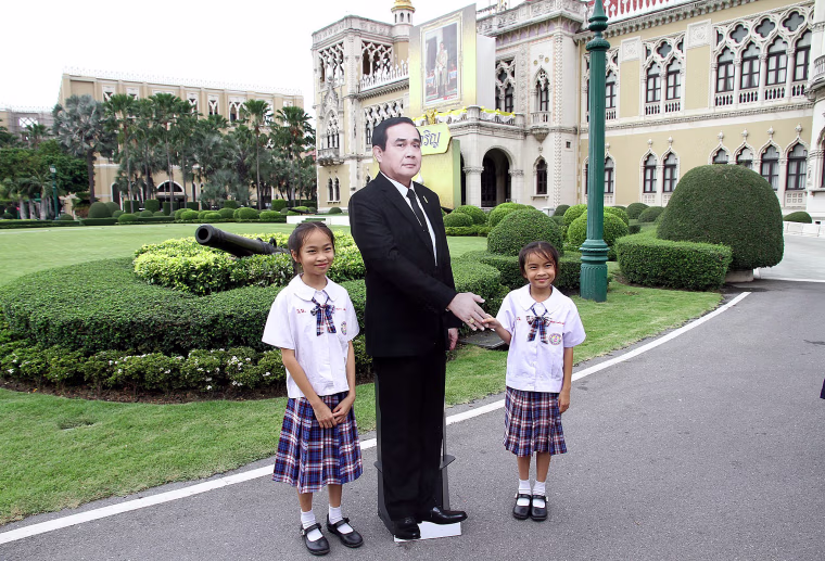 Image: Children pose next to a cardboard cut-out of Thailand's Prime Minster Prayuth Chan-ocha at the government house in Bangkok