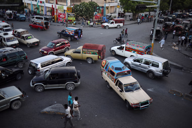 Image: Tap-tap trucks, collective transportation vehicles, and private cars drive in an intersection in Port-au-Prince