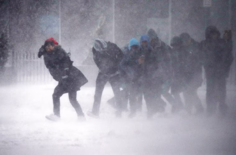 Image: People struggle to walk in the blowing snow during a winter storm