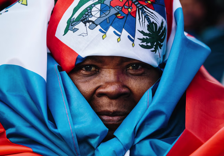 Image: A woman is wrapped in a Haitian flag at a rally against racism in New York