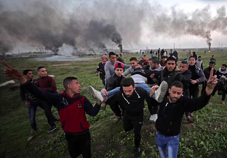 Image: Palestinian protesters carry a wounded man during clashes with Israeli troops