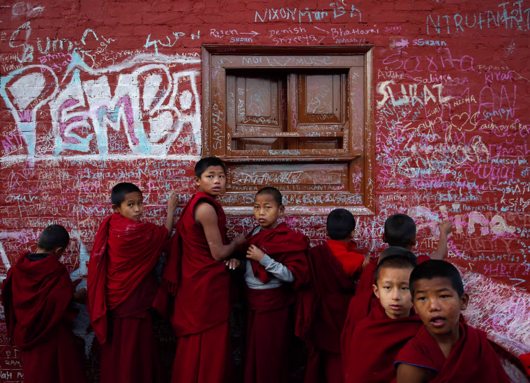 Image: Novice monks write on the wall of a Saraswati temple