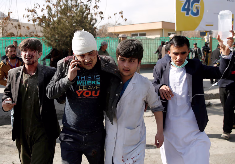 Image: People assist an injured man after a blast in Kabul
