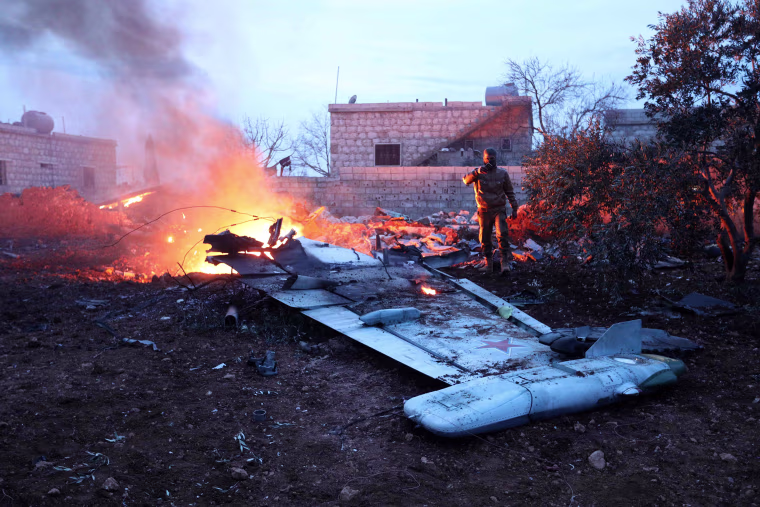 Image: A rebel fighter takes a picture of a downed fighter jet 