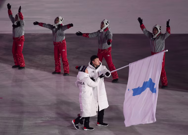 North Korean ice hockey player Hwang Chung Gum and South Korean bobsledder Won Yun-jong, right, wave a Korean unification flag as they lead the Korean delegation.