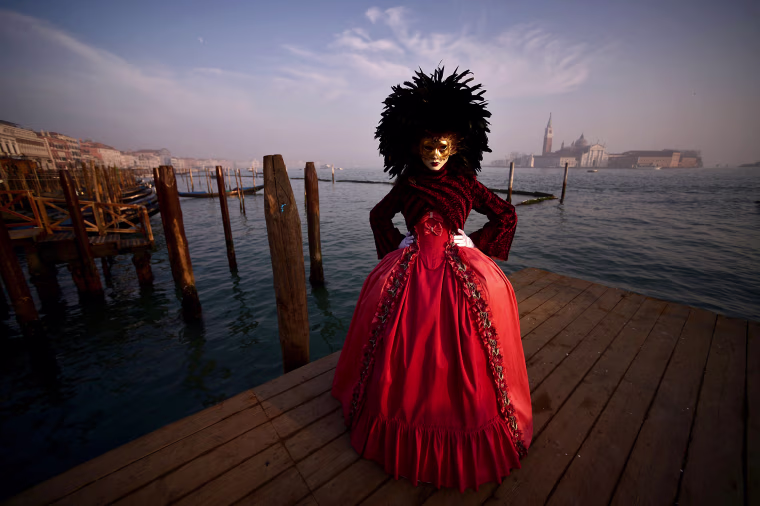 A masked reveller wearing a traditional carnival costume poses in St Mark Square during Venice's Carnival on Jan. 28, 2018.