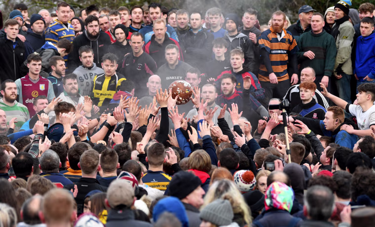 Image: Rival teams \"Up'ards\" and \"Down'ards\" battle for the ball during the Royal Shrovetide Football match in Ashbourne