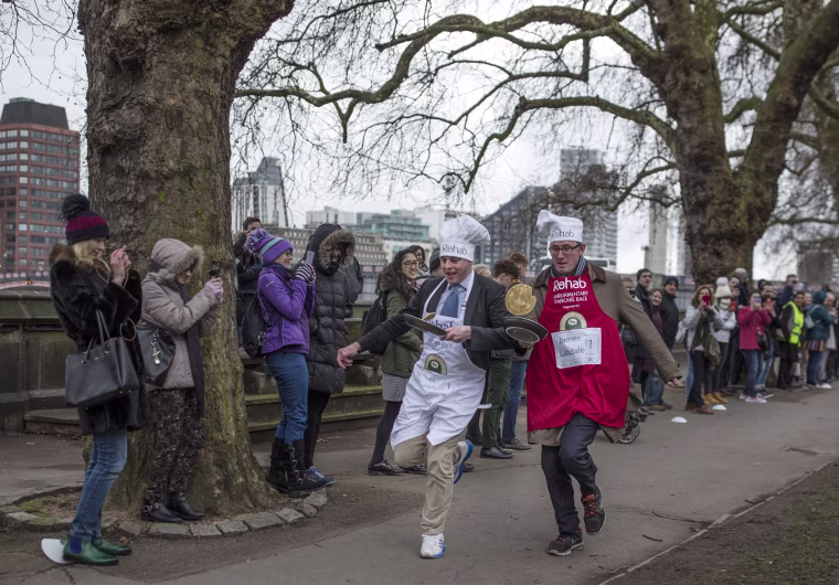 Image: The BBC's Diplomatic correspondent James Landale, right, and MP Matt Warman approach the first corner in the annual Parliamentary Pancake Race