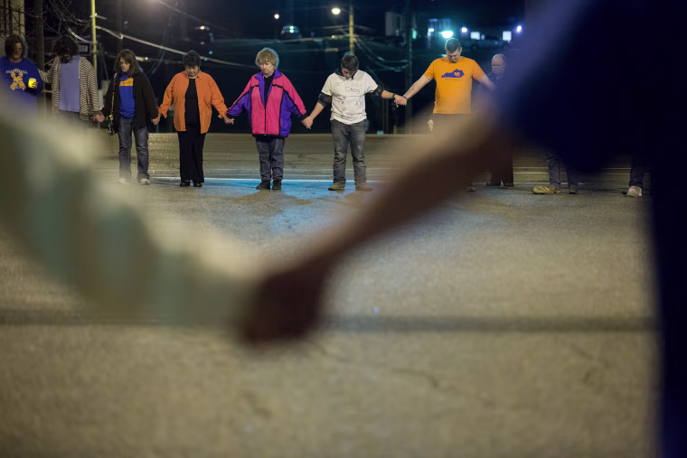 Mourners hold hands as they attend a vigil.