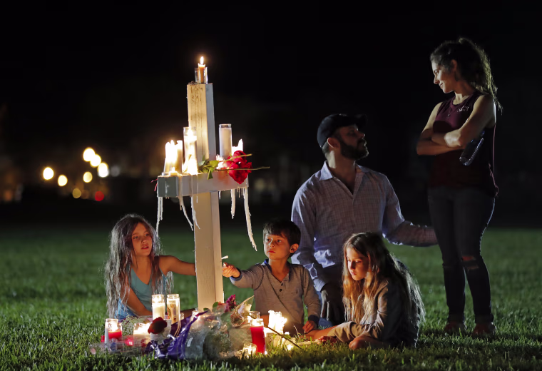 Rich and Rachel Castleberry visit one of seventeen crosses after a candlelight vigil with their children Mila, 9, left, Jack, 5, center, and Lucy, 7.