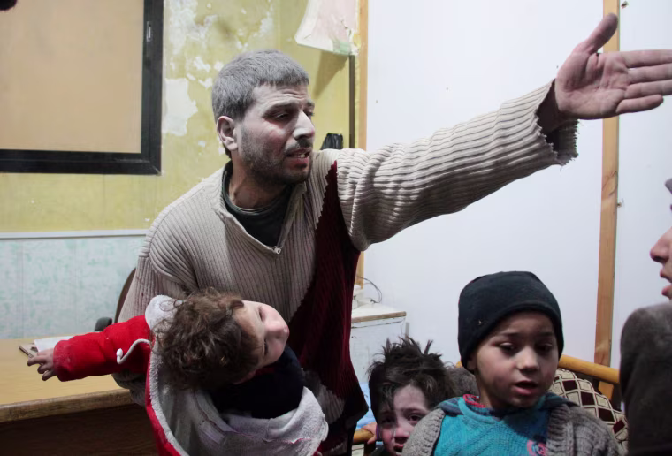 A Syrian man holds a child who was wounded in air strikes on the Syrian village of Mesraba in the besieged Eastern Ghouta region, at a make-shift hospital in Douma on Feb. 19.