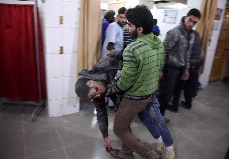 A man carries a severely wounded Syrian in Kafr Batna on Feb. 21.