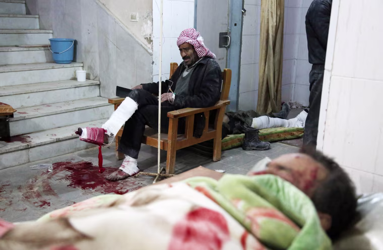 Wounded Syrians sit in wait in Kafr Batna on Feb. 21.
