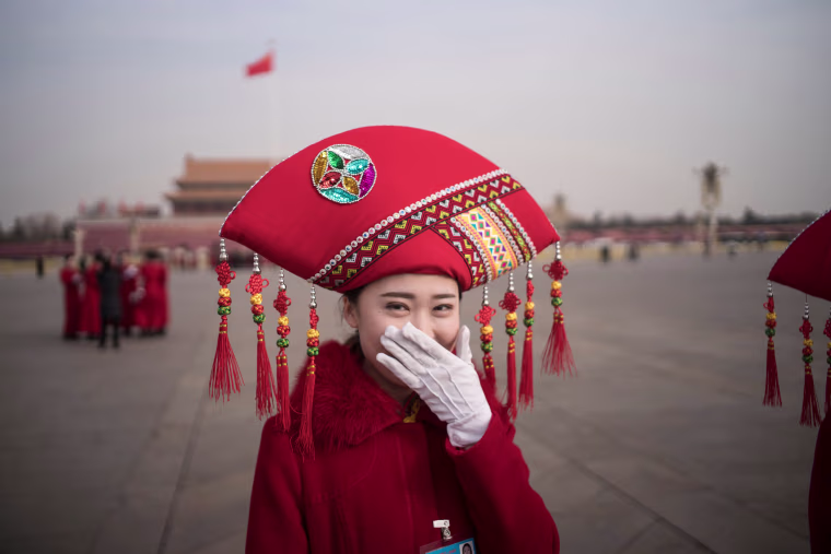 Image: A hostess smiles at Tiananmen Square during the opening session of the National People's Congress in Beijing