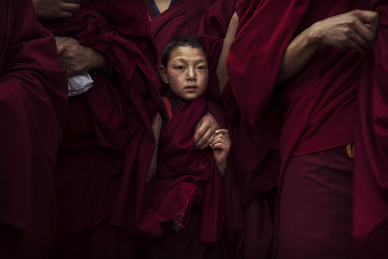 Image: A young monk waits before a Monlam procession near the Rongwo Monastery in Tongren