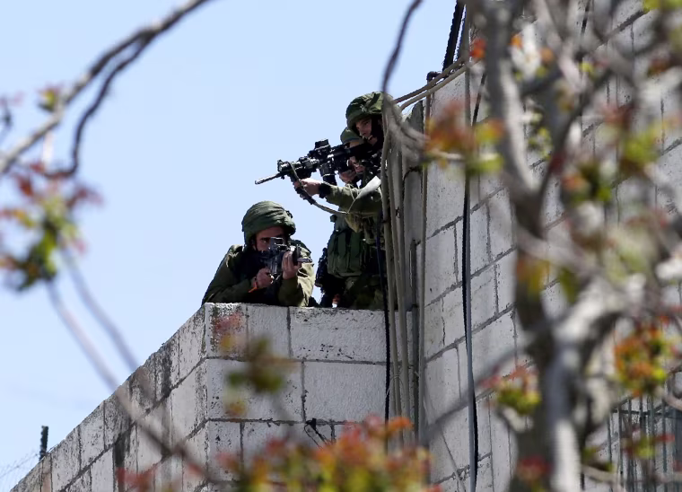 Israeli forces aim their weapons towards Palestinian demonstrators in the occupied West Bank city of Hebron on March 31.