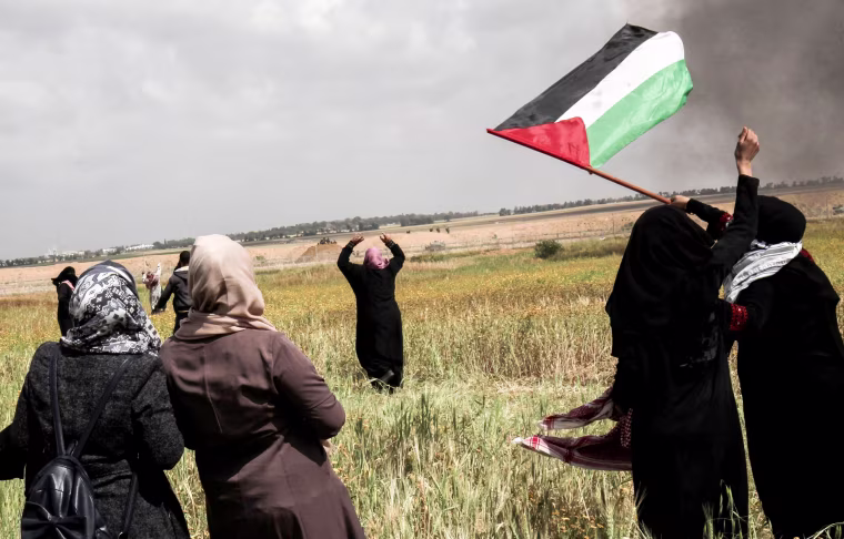 Palestinian women wave their national flag and gesture near the border, east of Khan Yunis, on March 30.