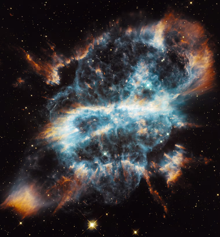 Hubble's website compares this bright gaseous nebula to a festive \"glass-blown holiday ornament with a glowing ribbon,\" but it more closely resembles a menacing skull to some people. Planetary nebulae represent the final brief stage in the life of a medium-sized star like our Sun. While consuming the last of the fuel in its core, the dying star expels a large portion of its outer envelope. This material then becomes heated by the radiation from the stellar remnant and radiates, producing glowing clouds of gas that can show complex structures, as the ejection of mass from the star is uneven in both time and direction.