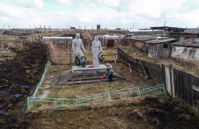 Image: A woman cleans the World War II monument in Irkutskoye