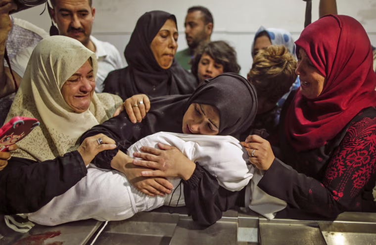Image: The mother of a Leyla al-Ghandour holds the body of her daughter