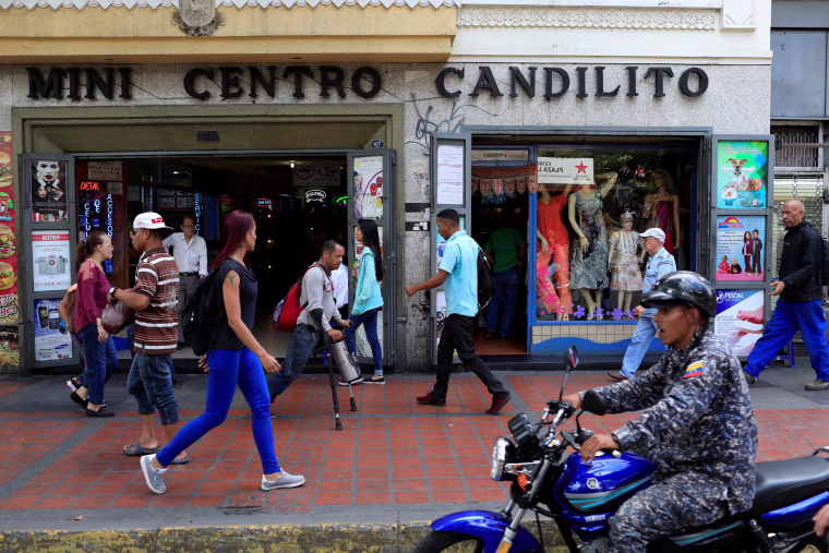 Image: People walk past stores in downtown Caracas
