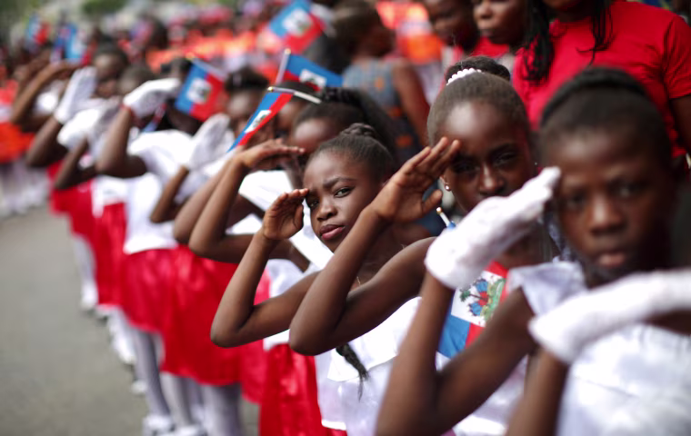 Image: Girls salute during celebrations for National Haitian Flag Day in the streets of Petion Ville, Port-au-Prince