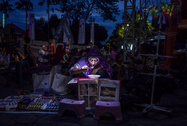 Image: A woman breaks her fast following the first day of Ramadan