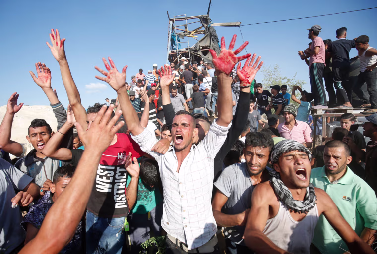 Image: Palestinians react with bloodied hands outside a Hamas outpost that was struck by Israeli bombardment near Khan Yunis in the southern Gaza Strip