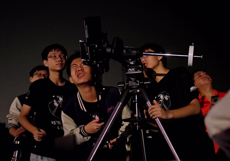 Image: Student astronomy enthusiasts adjust their telescope to see the lunar eclipse of a blood moon at Marina South Pier in Singapore