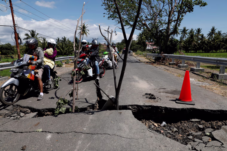 Image: A family rides on a motorcycle through a crack on the street at Kayangan district after earthquake hit on Sunday in North Lombok