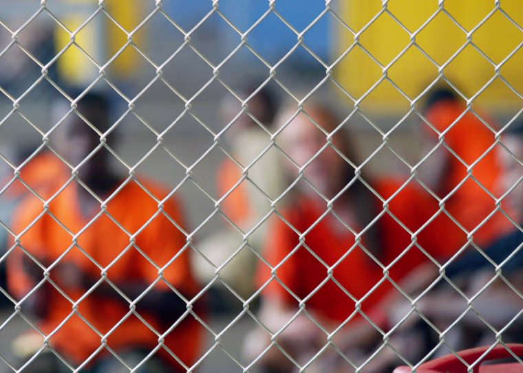 Inmates sit inside holding cell before being transported from New Orleans.