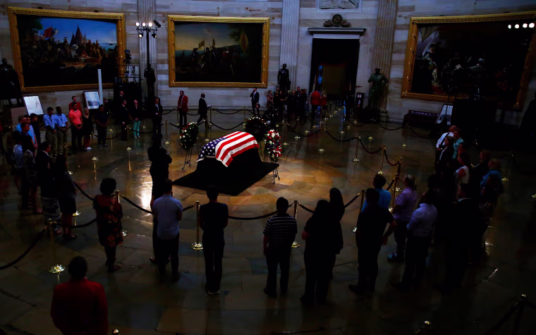 Image: Mourners look at the casket containing the body of late U.S. Senator John McCain as it lies in state inside the U.S. Capitol Rotunda in Washington