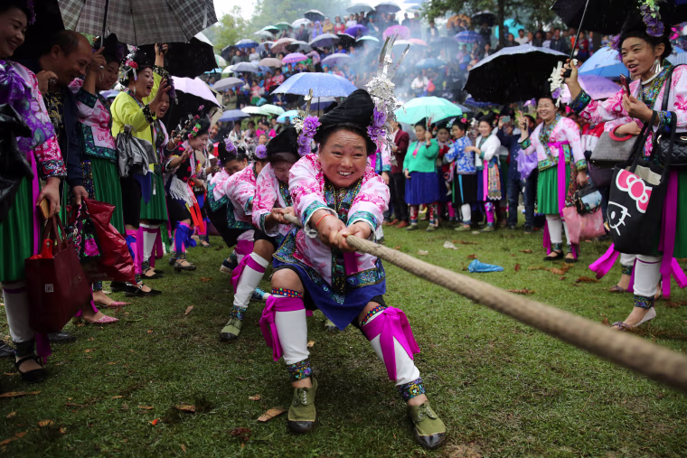 Image: Ethnic Miao women in traditional costumes take part in a tug of war to celebrate a local festival at a village in Rongshui Miao Autonomous County