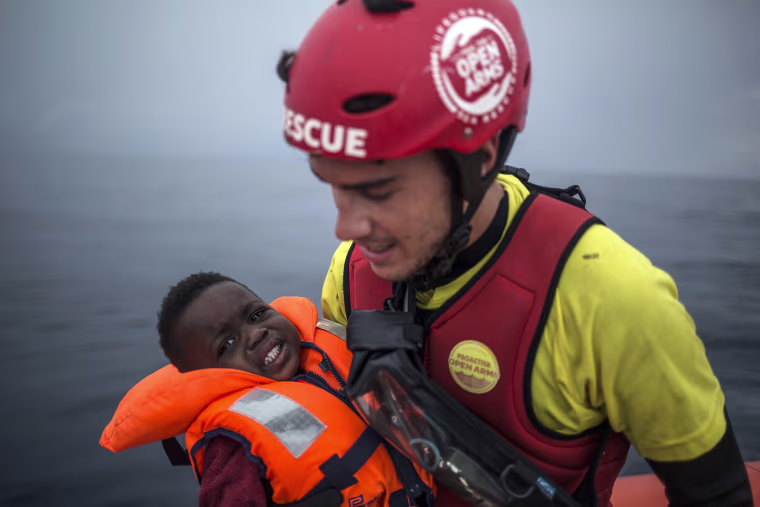 A member of Spanish NGO Pro activa Open Arms holds a baby rescued at a dinghy at Alboran Sea