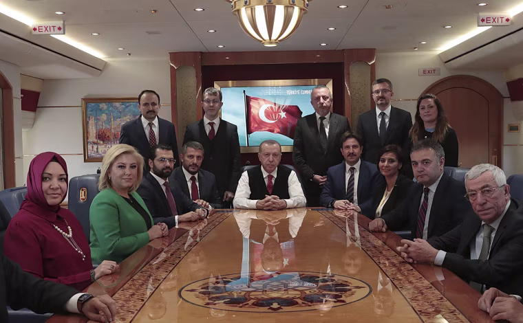 Image: Turkish President Recep Tayyip Erdogan poses for photos with Turkish journalists aboard his plane