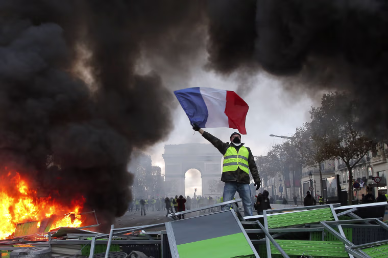 Image: A demonstrator waves the French flag on the Champs-Elysees