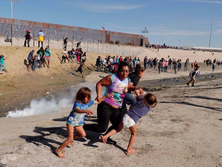 Image: A family runs away from tear gas in front of the border wall between the U.S. and Mexico, in Tijuana