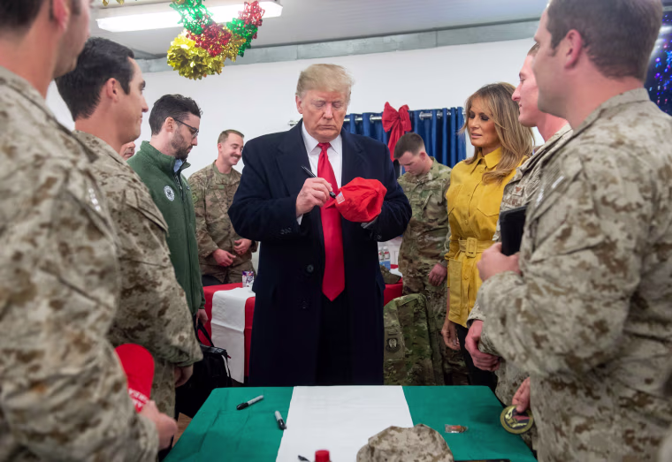 Image: President Donald Trump signs a hat at Al Asad Air Base in Iraq.