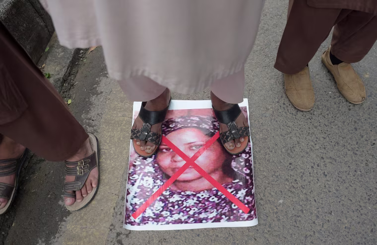 A protester stands on an image of Aasia Bibi in November.