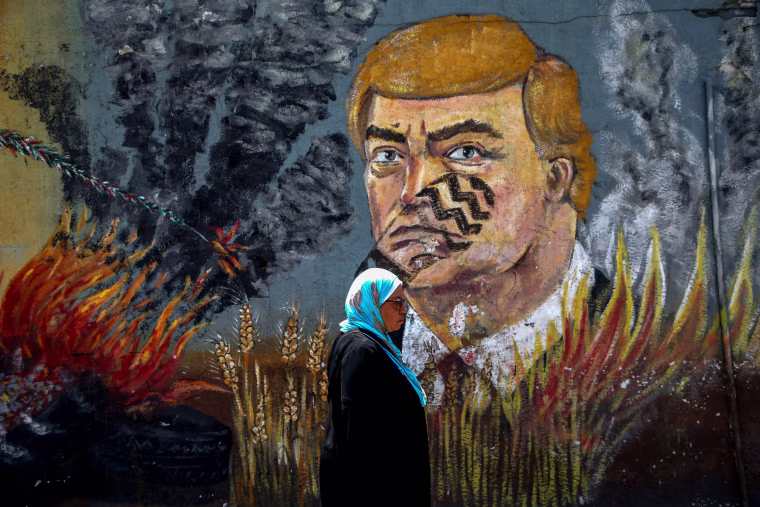 Image: A woman walks past graffiti depicting President Donald Trump with a footprint on his face in Gaza City on June 23, 2019.