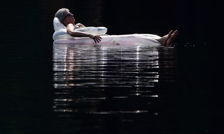 Image: A woman floats on an air mattress in Mazinaw Lake at Bon Echo park in Cloyne