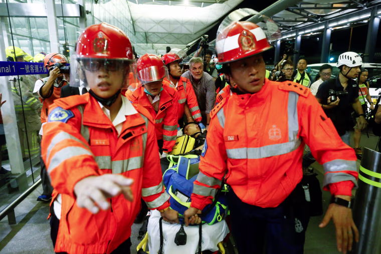 Image: Medics remove an injured man who anti-government protesters said was an undercover policeman at the airport in Hong Kong