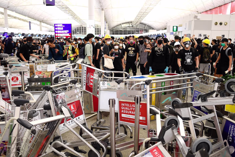 Image: Pro-democracy protesters block the entrance to the airport terminals after a scuffle with police at Hong Kong's international airport