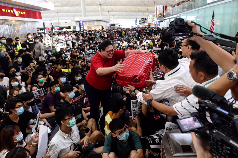 A tourist gives her luggage to security guards as she tries to enter the departures gate during a demonstration by pro-democracy protesters at Hong Kong's international airport on Aug. 13, 2019.