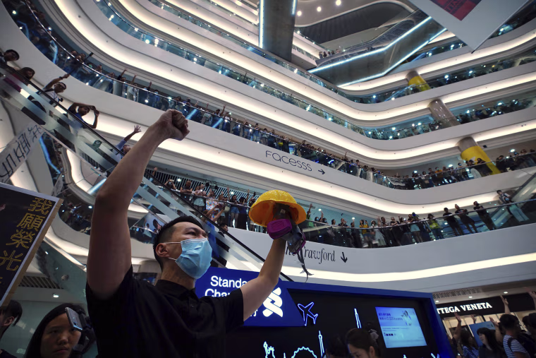 Image: Demonstrators sing a theme song written by protestors "Glory to Hong Kong" at the Times Square shopping mall in Hong Kong