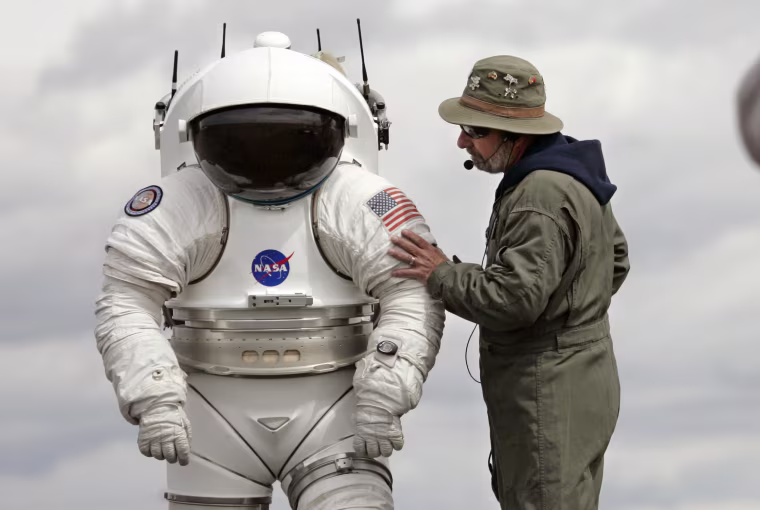 Technician Bill Welch, left, stands inside a 300-pound space suit as another technician talks with him June 10, 2008, in Moses Lake, Wash. NASA scientists and contractors spent two weeks in Moses Lake field testing some of the vehicles and robots that will be used when humans return to the moon later this century. (AP Photo/Elaine Thompson)